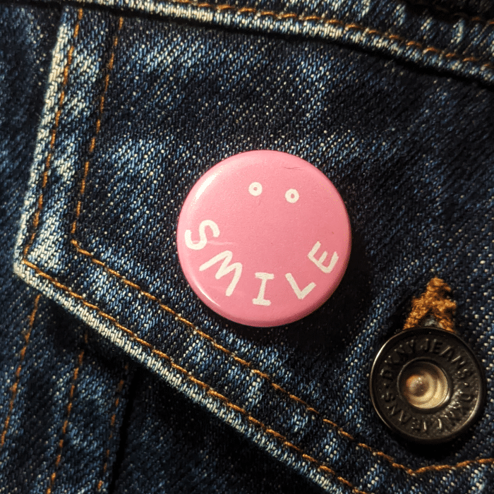 smile button worn on a jean jacket